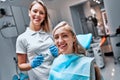 Portrait of a woman with toothy smile sitting at the dental chair with doctor on the background at the dental office