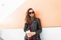 Portrait woman in trendy red-black youth clothes from new collection with cup tea or coffee rest near modern wall on street. Royalty Free Stock Photo