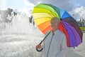 Portrait of a woman under a rainbow umbrella against the background of a fountain Royalty Free Stock Photo