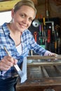 Portrait Of Mature Woman Upcycling Furniture In Workshop At Home Painting Cabinet