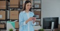 Portrait of a woman using a smartphone at work in a warehouse. A woman connects to customer support via the Internet Royalty Free Stock Photo
