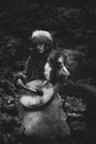 Portrait of a woman wearing fur hat and fox fur pelt on her shoulders.Playing shamanic drum.Shot in forest surroundings. Royalty Free Stock Photo