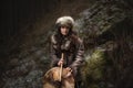 Portrait of a woman wearing fur hat and fox fur pelt on her shoulders.Playing shamanic drum.Shot in forest surroundings.