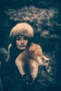 Portrait of a woman wearing fur hat and fox fur pelt on her shoulders.Shot in forest surroundings. Royalty Free Stock Photo