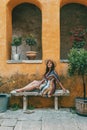 Portrait of woman wearing hat and dress, sitting in front of old orange building Royalty Free Stock Photo