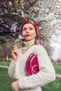 Portrait of woman wearing red hair scarf in spring park. Retro female fashionable accessories. Headscarf and purse Royalty Free Stock Photo