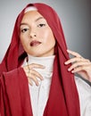 Portrait of a woman wearing a red hijab against grey studio background and copyspace. Young muslim lady wearing a Royalty Free Stock Photo