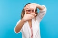 Portrait of woman in white jacket looking through photo frame made of hands. , blue background Royalty Free Stock Photo