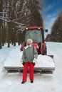 Portrait a woman in winter clothes against the background of a tractor with snow Royalty Free Stock Photo