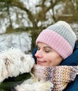 Portrait of a woman in winter clothes with her puppy dog. Happy woman and little maltese pet together. Royalty Free Stock Photo
