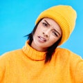 Portrait of woman in winter fashion with confusion, beanie and doubt isolated on blue background. Style, funny