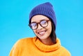 Portrait of woman in winter fashion with smile, beanie and glasses isolated on blue background. Style, happiness and gen Royalty Free Stock Photo
