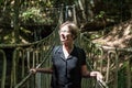 Portrait of a woman at a wooden suspension bridge over a small creek valley in the woods Royalty Free Stock Photo