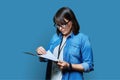 Portrait of woman worker with industrial center card clipboard, on blue background