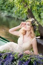 Portrait of woman with wreath sitting in boat with flowers. Summer Royalty Free Stock Photo