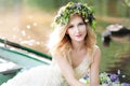 Portrait of woman with wreath sitting in boat with flowers. Summer