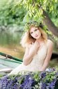 Portrait of woman with wreath sitting in boat with flowers. Summer