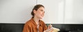 Portrait of woman writing down her ideas in a notebook, holding pen and looking thoughtful, inspired to write in diary