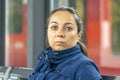 Portrait of a woman 40-45 years old, sitting at a bus stop at the railway station, waiting for her train. Royalty Free Stock Photo