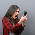 Portrait of a woman yelling at phone against gray background Royalty Free Stock Photo