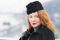 Portrait of woman in black coat and black hat. Closeup of rouge woman with red lips. Beautiful lady in coat on city background Royalty Free Stock Photo