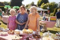 Portrait Of Women Serving On Cake Stall At Busy Summer Garden Fete