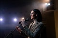 Portrait of women speaking through a microphone in dark conference hall. woman talks into microphones at press Royalty Free Stock Photo