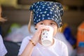 The portrait of wondered blonde girl with two braids drinking her tea