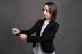 Portrait of wonderful young business woman arranges her suit sleeve, poseing on isolated gray background