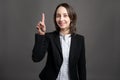 Portrait of wonderful young business woman with her finger up has come up with an idea, poseing on isolated gray background Royalty Free Stock Photo
