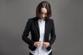 Portrait of wonderful young business woman arranges her suit poseing on isolated gray background