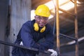 Portrait worker man with yellow helmet and ear protection in factory, Dark tone