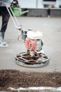 Portrait of worker using sand and cement power trowel tool, screed laying and finishing on construction site Royalty Free Stock Photo