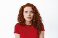 Portrait of worried and concerned ginger girl looking at camera anxious, hear bad news and feel scared, standing against