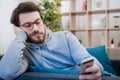 Portrait of worried man on the sofa holding cellphone at home Royalty Free Stock Photo