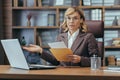 Portrait of a worried senior businesswoman in a business suit sitting in the office at a desk, holding a letter in an Royalty Free Stock Photo