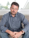 Portrait of worried senior man sitting on sofa in living room Royalty Free Stock Photo