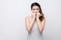 Portrait of worry beautiful young brunette woman with striped dress standing, looking away and bitting her nails with stressed