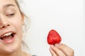 Portrait of yaung woman eating strawberries.