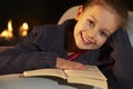 Portrait 7 year old girl reading by firelight Royalty Free Stock Photo