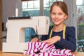 Girl sewing a pink and white striped cloth with a sewing machine