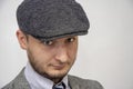 Portrait of a 35-year-old man with a beard in a suit and cap on a gray background, close-up, selective focus. Royalty Free Stock Photo