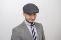 Portrait of a 35-year-old man with a beard in a suit and cap on a gray background, close-up, selective focus. Royalty Free Stock Photo