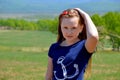 Portrait of 10 year old Russian blonde girl with long hair, hair band on a background of green field. cute face, looking at the ca Royalty Free Stock Photo