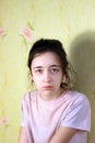 Portrait of a 12-year-old teenage girl with a serious face at home, natural skin on her face, not retouched. Patience and calmness