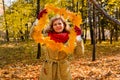 Portrait of a 40-year-old woman in a frame of maple leaves in an autumn park. Autumn concept