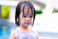 Portrait of 4-5 years old of Asian child girl wearing purple swimming suit. Kid body wet from water in the pool.