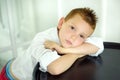 Portrait of 7 years old caucasian boy in white shirt with his hands near face. Fashionable good looking little boy looking in Royalty Free Stock Photo