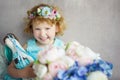 Portrait of 5 years old curly blonde laughing girl in blue dress and wreath with rabbit toy in hands. Waiting for spring small Royalty Free Stock Photo