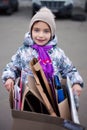 Portrait of 7 years old girl with big box of cardboard for recycling near waste sorting station in Kyiv, Ukraine. Concept of eco,